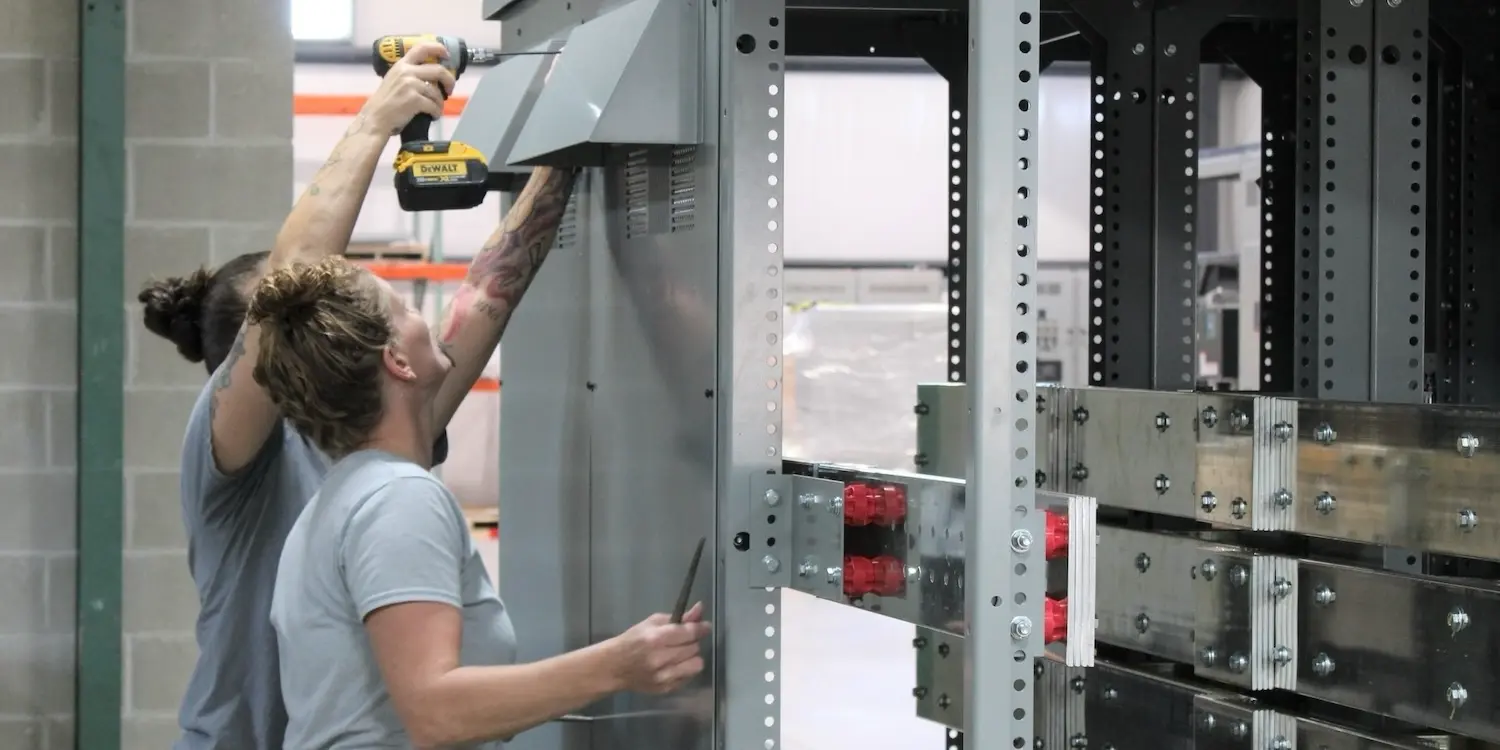 Two workers building a generator enclosure